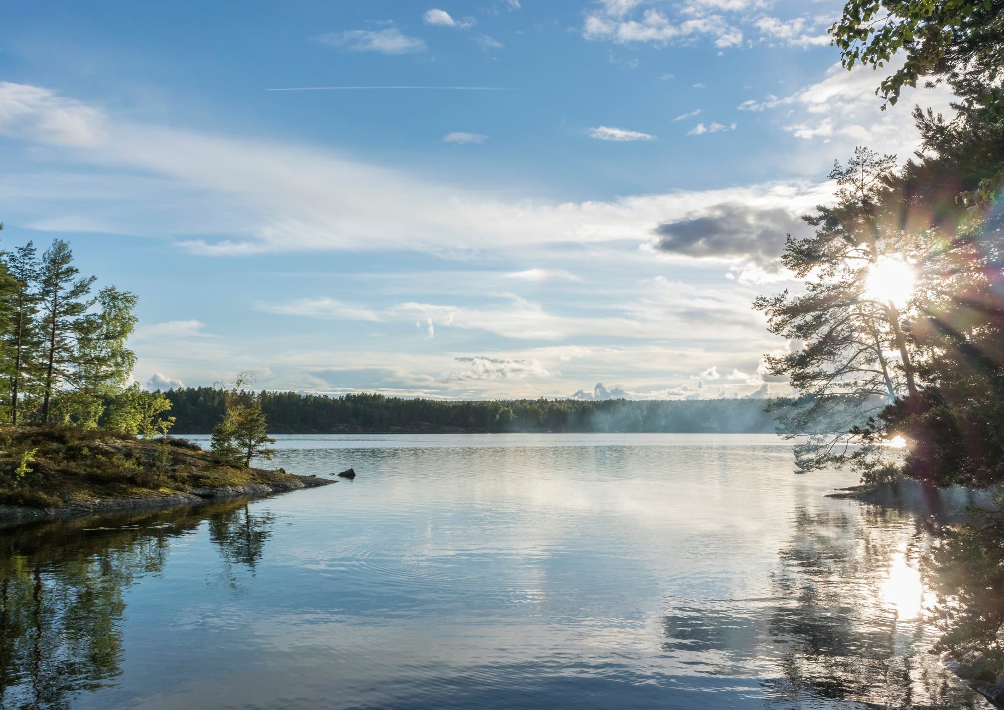 Stiller See mit bewaldeten Inseln bei Sonnenaufgang