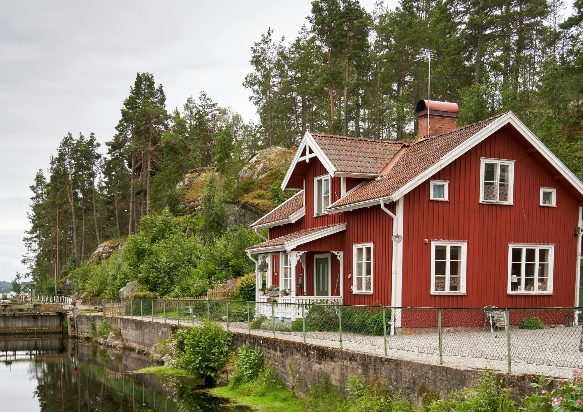 Rotes Holzhaus am Wasser zwischen Kiefern