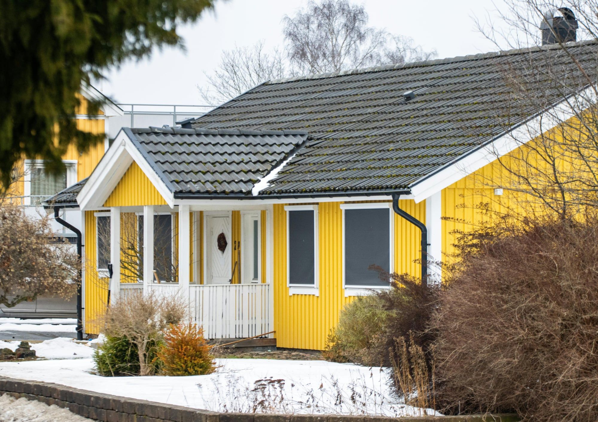 Gelbes Holzhaus mit Veranda im Winter